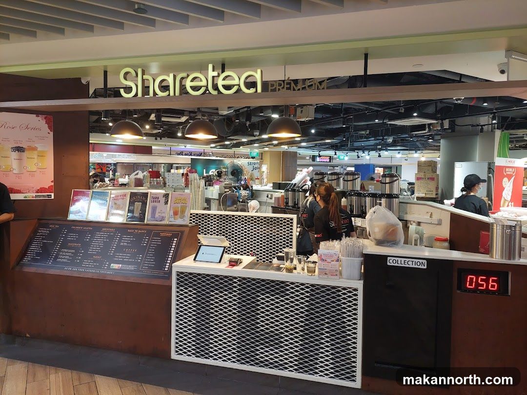 A Sharetea shop front with a large menu board and staff preparing drinks. The shop's name is displayed prominently above the counter.