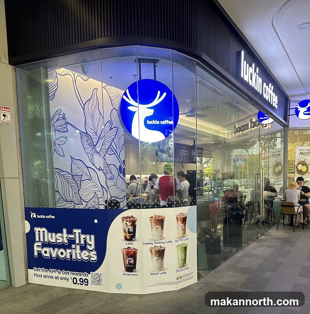 A Luckin Coffee store with large glass windows and a prominent blue and white logo featuring a deer. The storefront displays a promotional poster for "Must-Try Favorites" with images of various coffee drinks and a special offer for the first drink at $0.99. Inside, customers and staff are visible.