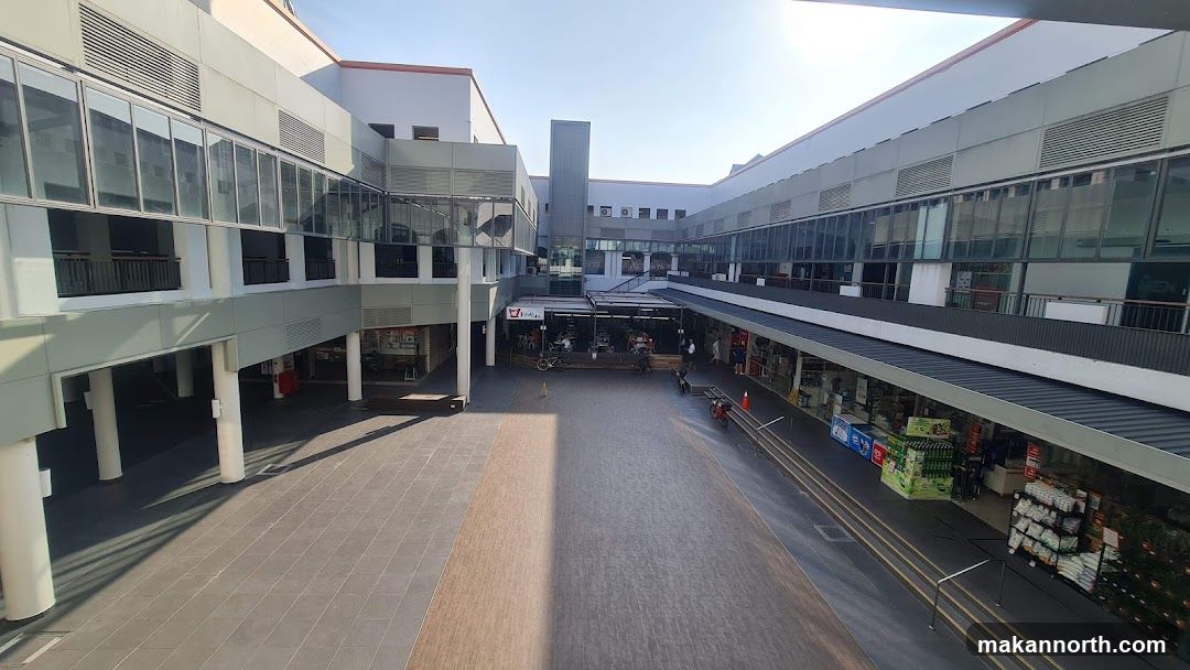 Outdoor shopping complex with shops and seating areas