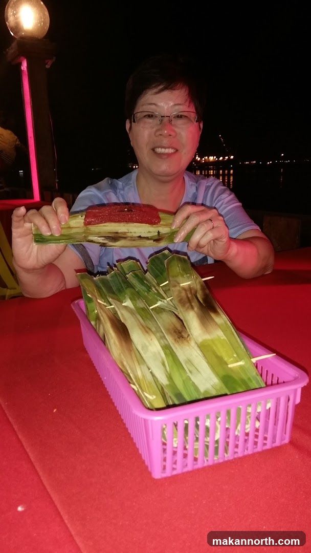 Woman with grilled fish in banana leaves