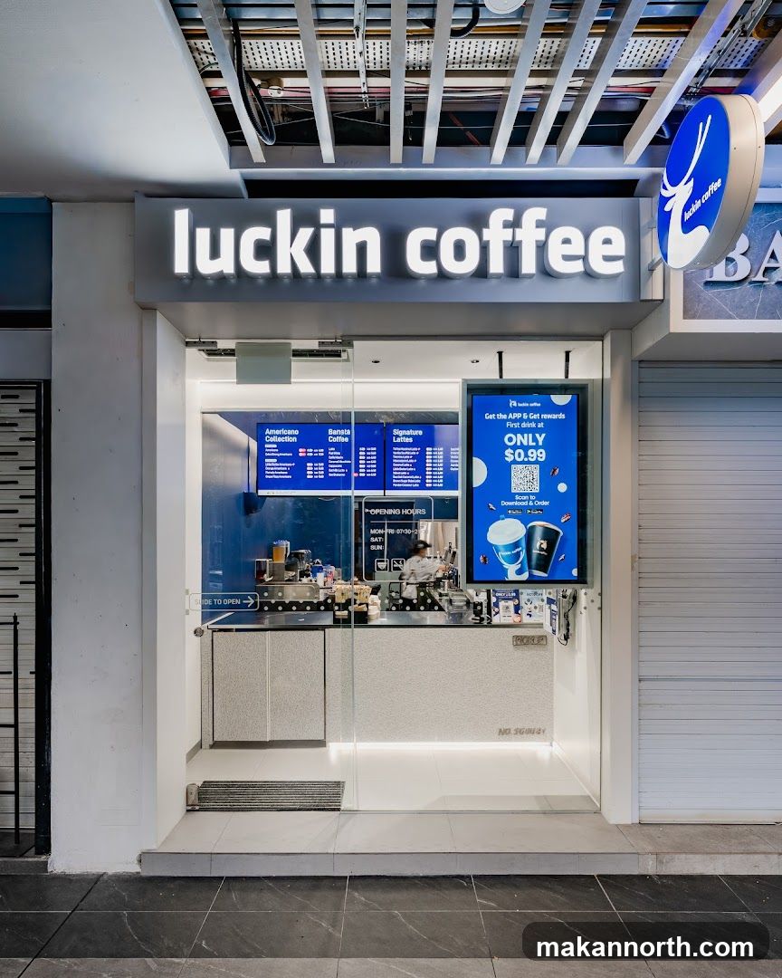 A modern Luckin Coffee storefront with a prominent illuminated sign above the entrance. Inside, a digital menu board displays various coffee options and promotions. The counter area is visible, with baristas preparing drinks. A sign indicates opening hours and a QR code for app downloads.