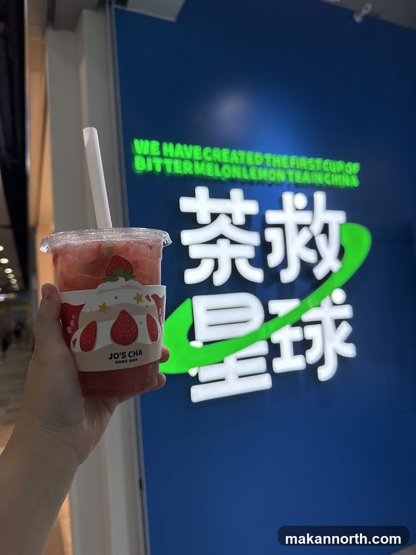 Hand holding a strawberry drink in front of a store sign