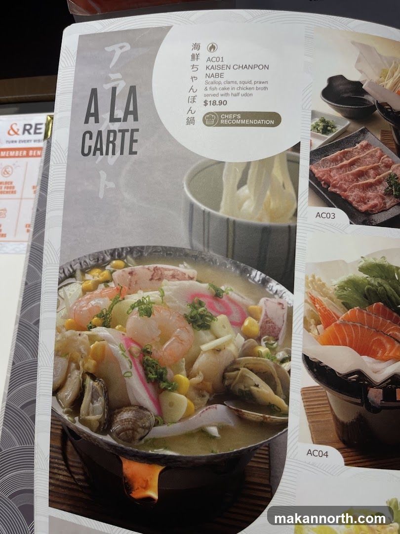 A menu page with Japanese dishes. The main dish featured is KAISEN CHANPON NABE, a seafood noodle soup with scallops, clams, squid, prawn, and fish cake in chicken broth, served with half udon for $18.90. It is marked as a Chef's Recommendation. Other items shown are AC03 (raw meat slices) and AC04 (salmon sashimi).