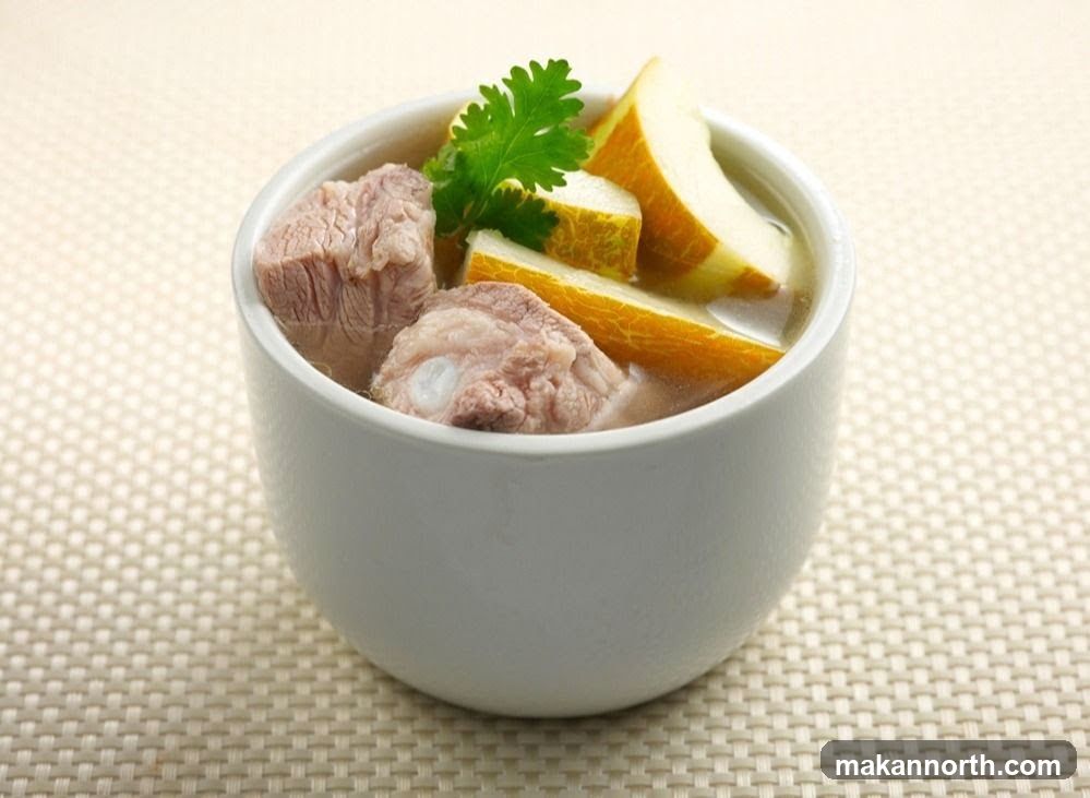 A white bowl filled with pork rib and melon soup. The soup contains several pieces of pork rib and slices of melon, garnished with a sprig of cilantro. The bowl is placed on a textured beige placemat.