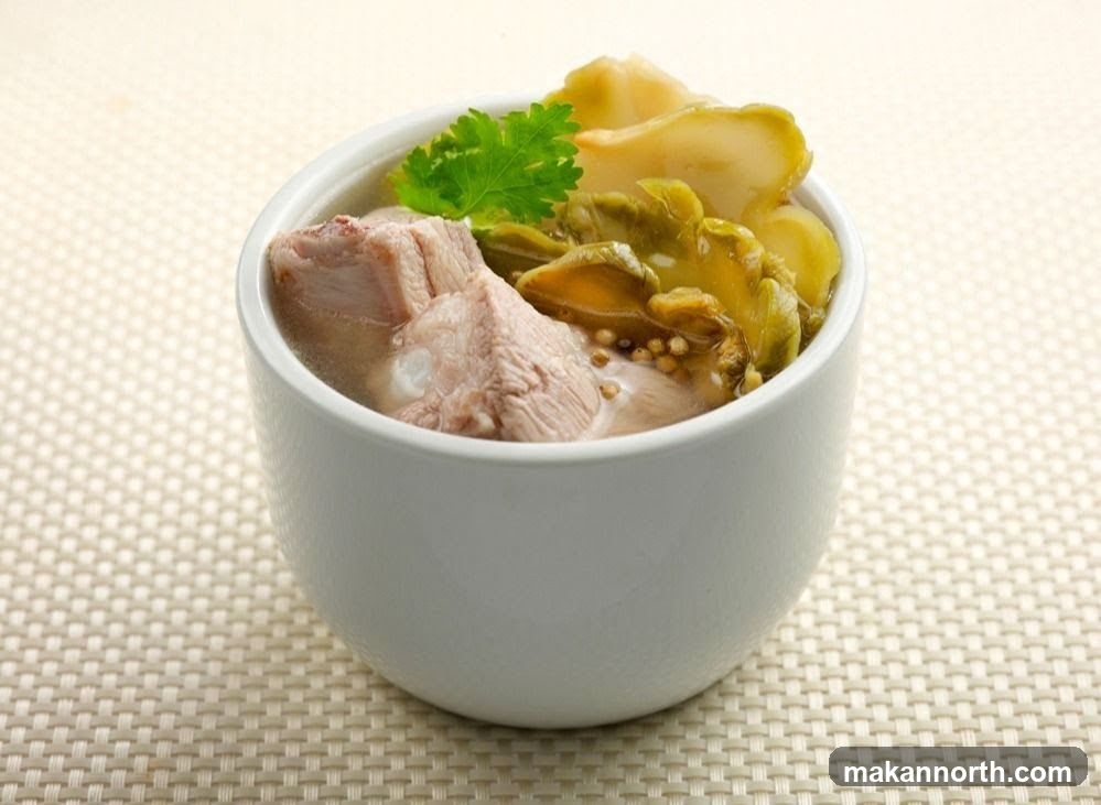 A white bowl filled with a savory soup containing chunks of pork ribs and pickled mustard greens. A sprig of cilantro garnishes the top. The bowl sits on a textured, light-colored placemat.