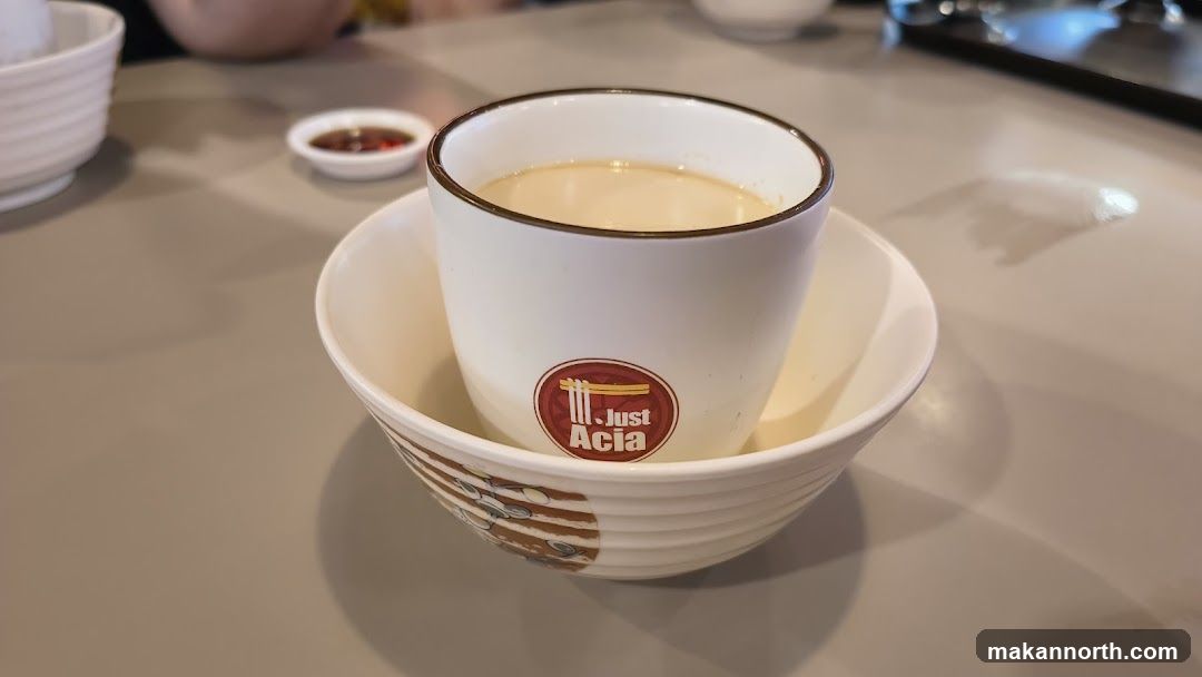 A cup of creamy liquid in a bowl with a logo