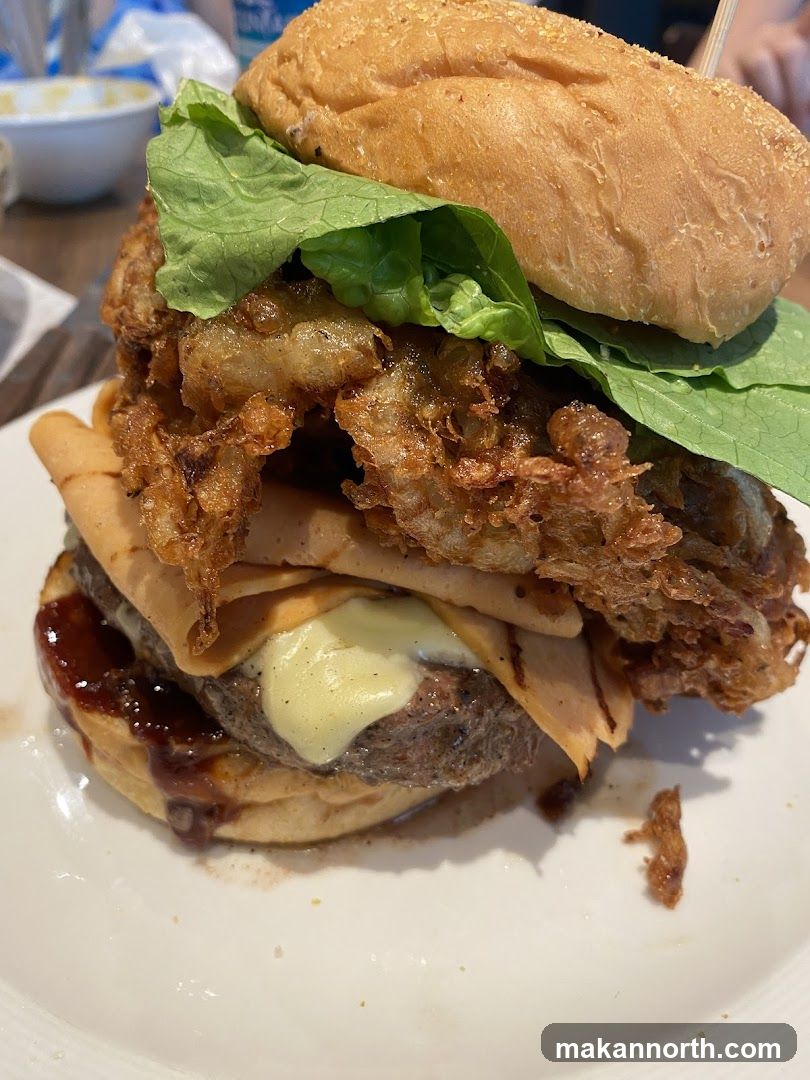 A tall burger on a white plate.