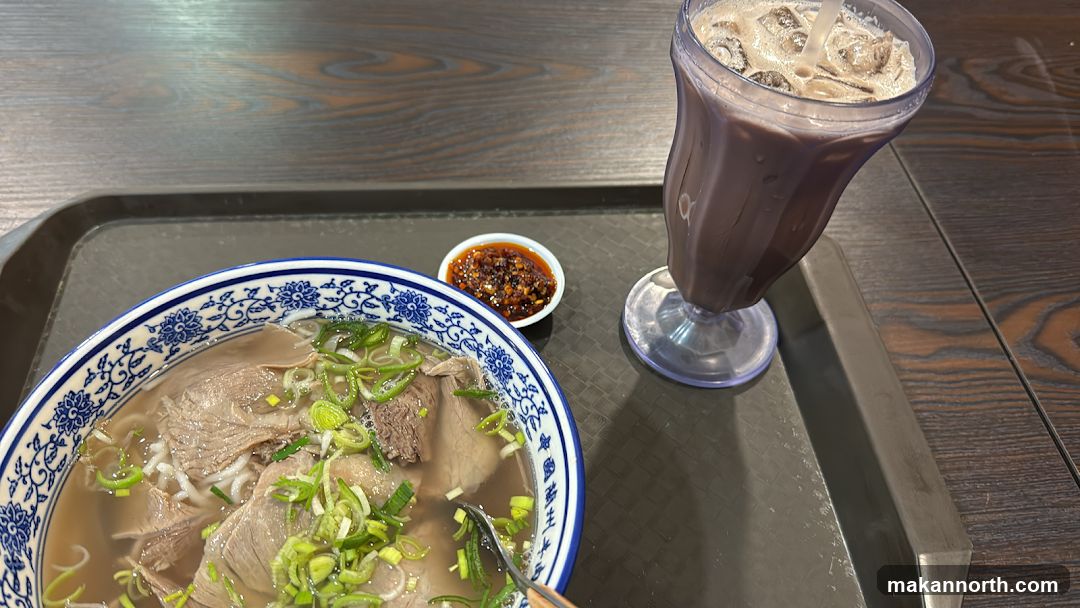 Beef noodle soup with a side of chili and a chocolate drink