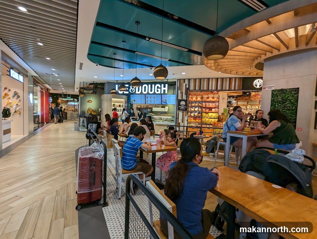 People dining at tables inside a mall food court