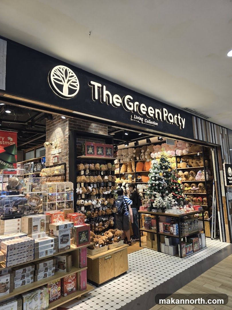 The exterior of a store called "The Green Party Living Collection". The storefront is decorated with a Christmas tree and displays of stuffed animals and gift boxes.
