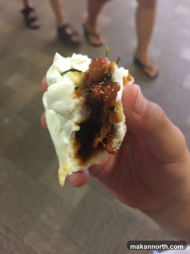 Hand holding a steamed bun with filling